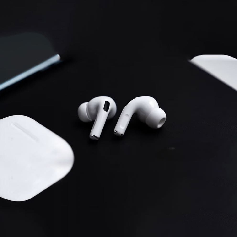 White wireless earbuds with charging case on a black surface