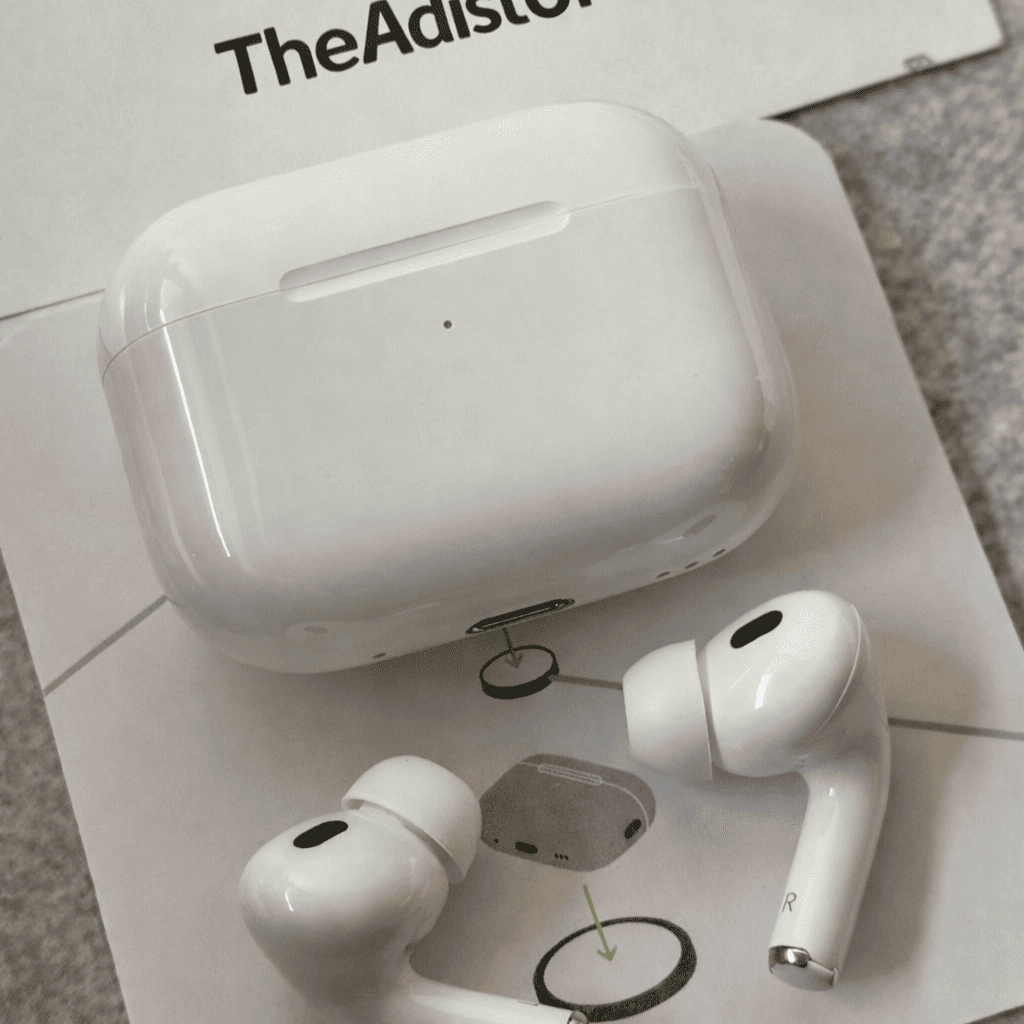 White Adipods Pro 2 wireless earbuds with charging case on a magazine