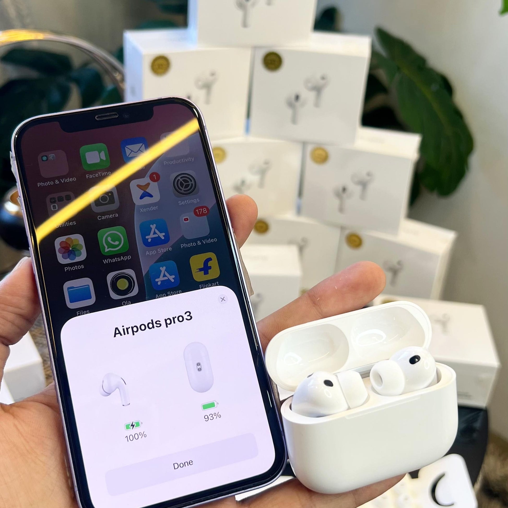 Person holding a smartphone displaying Adipods Pro 3 on screen with Adipods Pro 3 in a case.