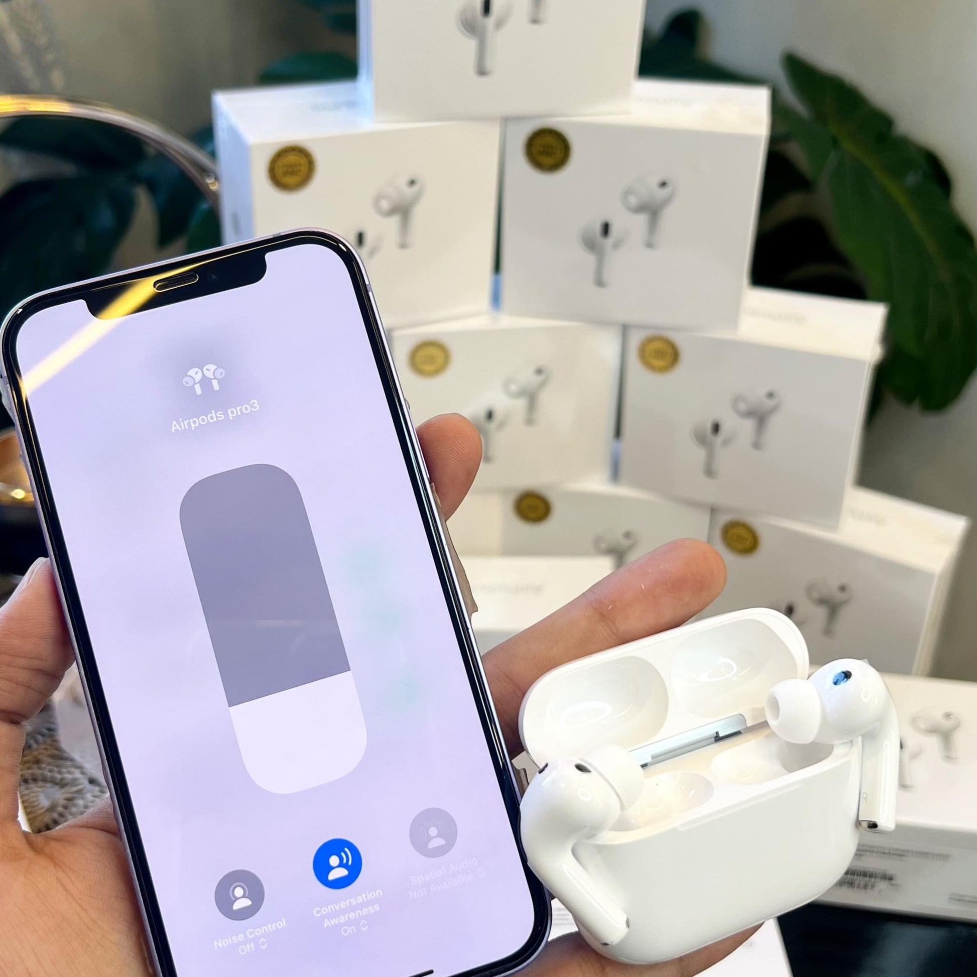 Person holding a smartphone with Adipods Pro 3 earbud case and wireless earbuds in front of product packaging.