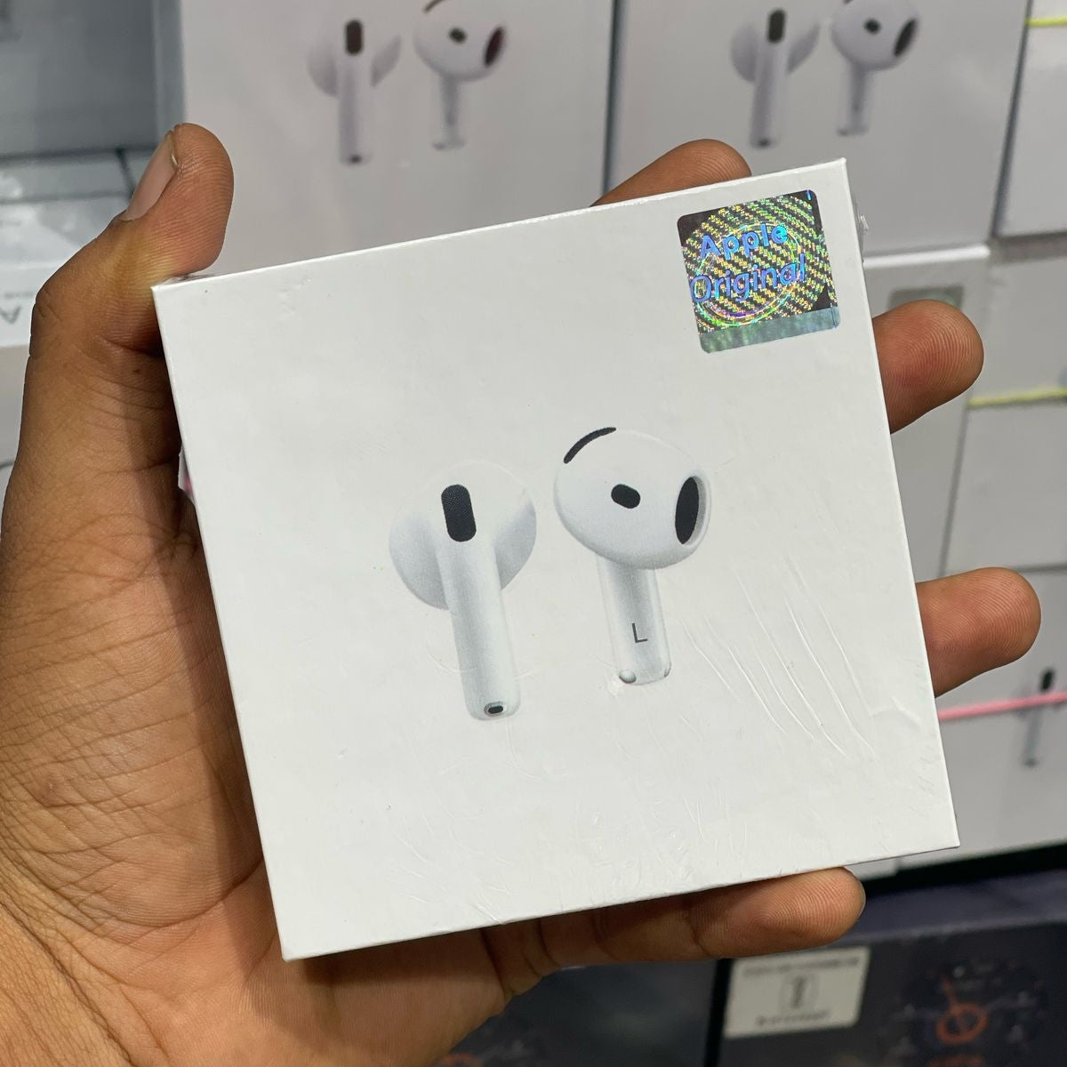 Hand holding a Adipods Pro 4 earbud illustrations, likely containing wireless earbuds.