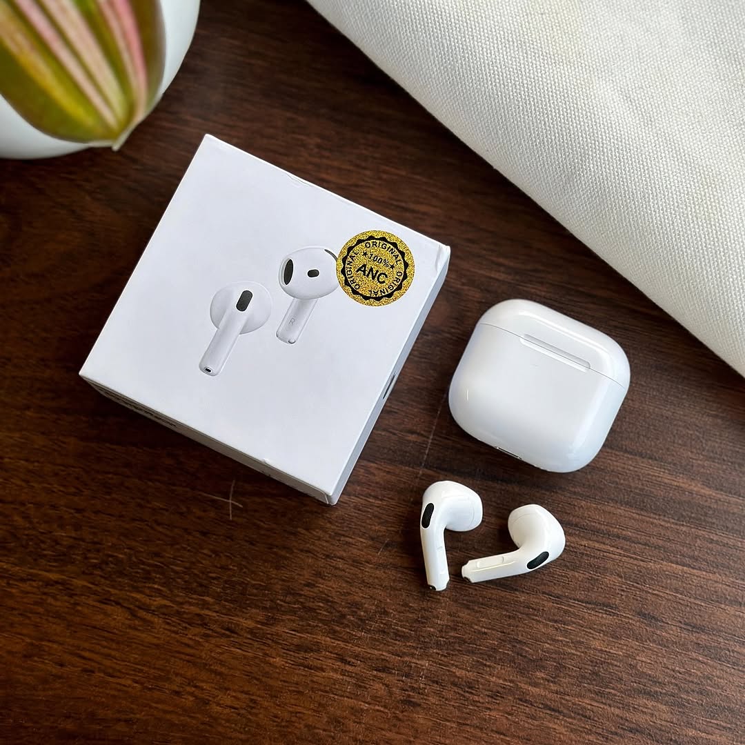 White Adipods Pro 4 wireless earbuds with charging case on a wooden surface next to their packaging.